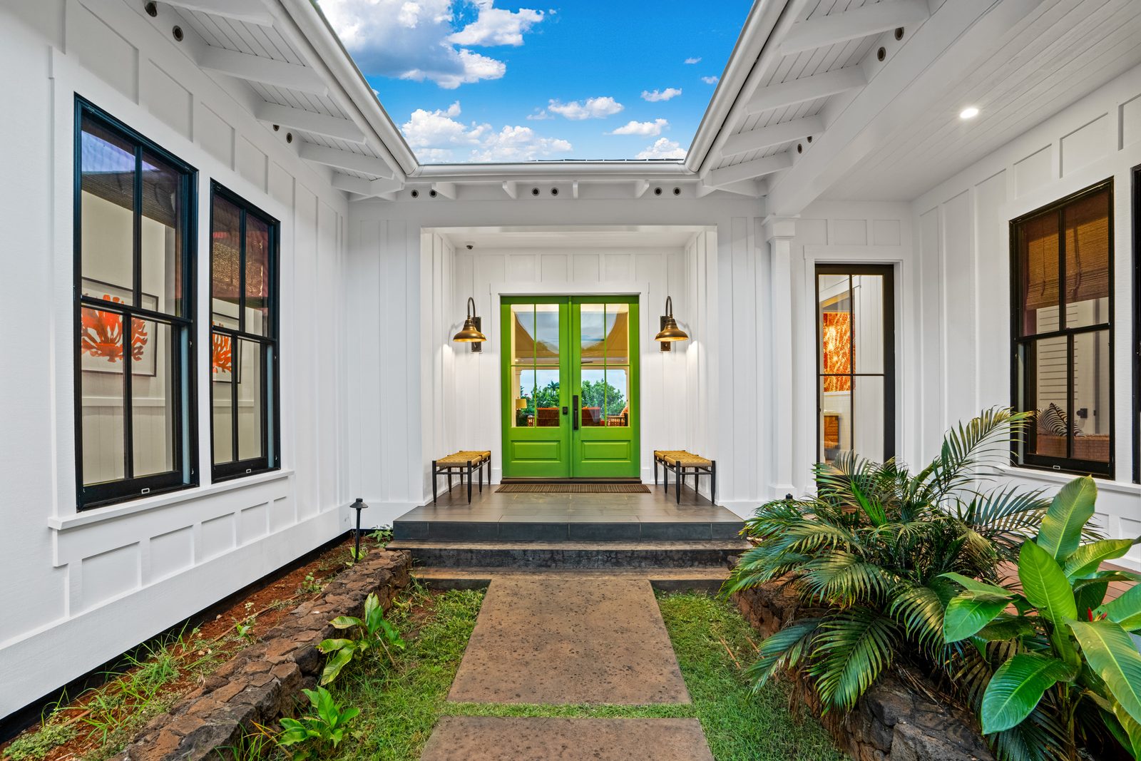 The front entry with green double doors and lantern sconces