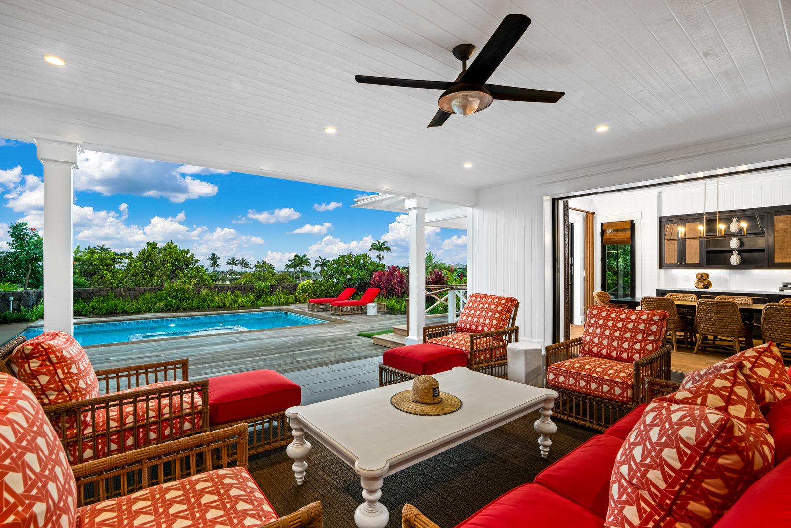 Covered lanai seating in coral prints, looking out to the pool