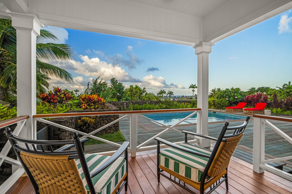 Cane chairs on the lanai with the pool and sky beyond