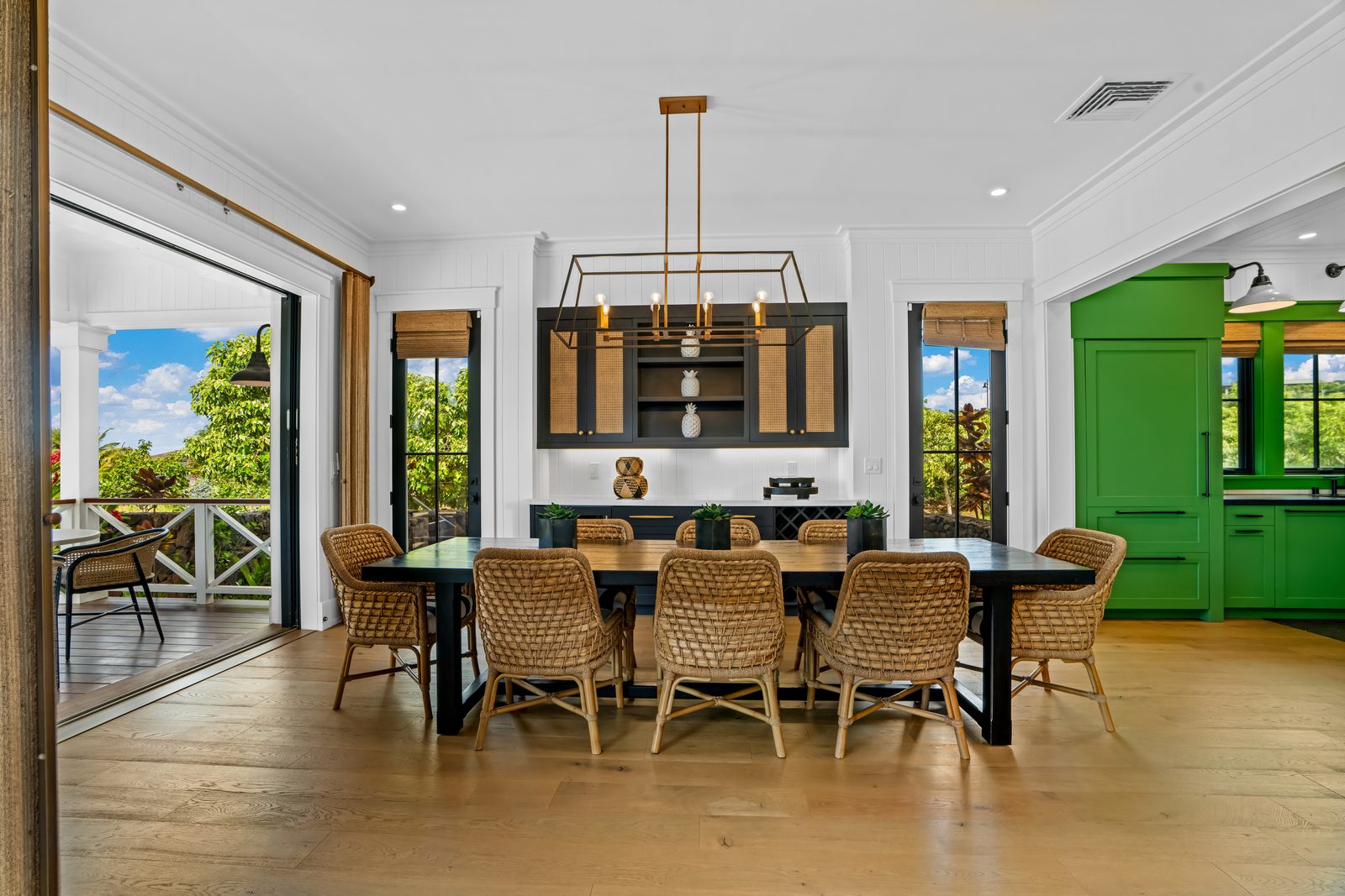 The dining room with a long table, woven chairs and a green door