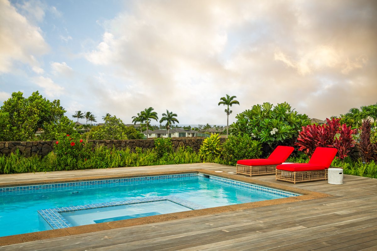 The pool at sunset, palms and loungers against a pale sky
