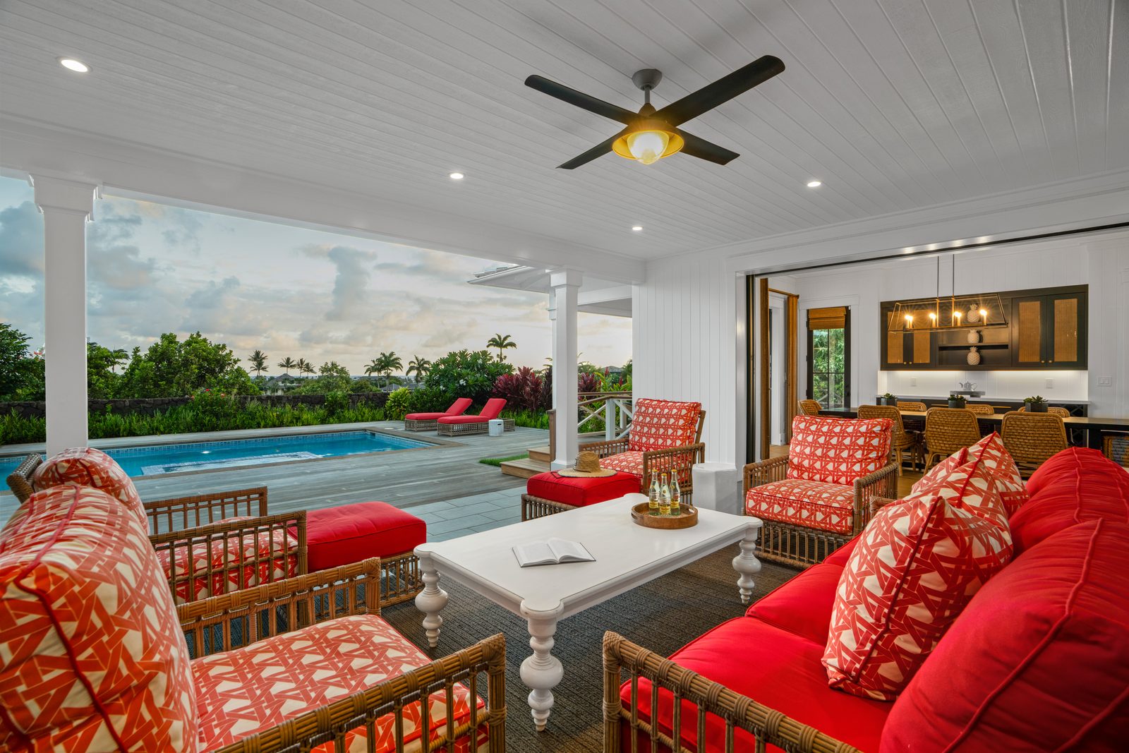 The covered lanai in coral cushions, open to the pool