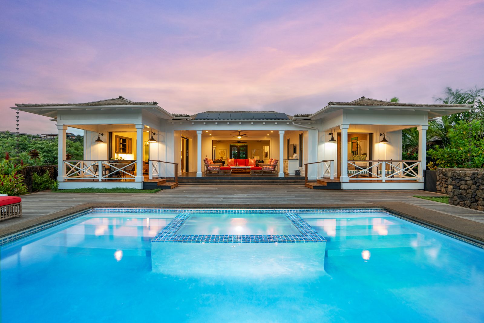 The house seen across the pool, lit from inside